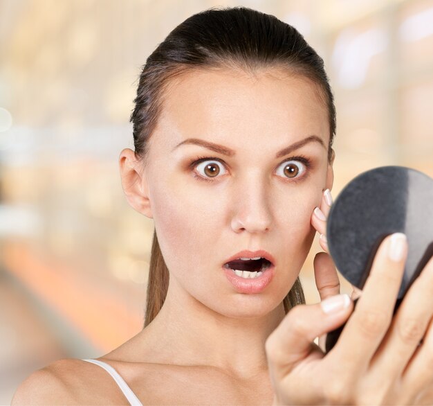 Photo portrait of young attractive woman touching her face and looking for acne