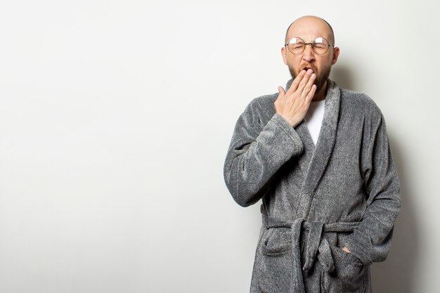 Photo portrait of a young bald man with a beard in a bathrobe and glasses