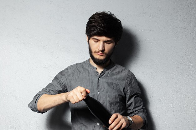 Portrait of young bearded guy, opens steel thermo black bottle for water