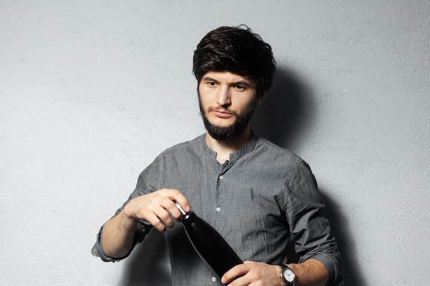 Portrait of young bearded guy, opens steel thermo black bottle for water