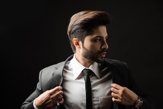 Портрет молодого бородатого индийского бизнесмена на черном фоне, угрюмое освещение
