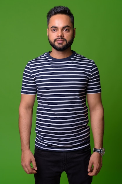 portrait of young bearded Indian man on green