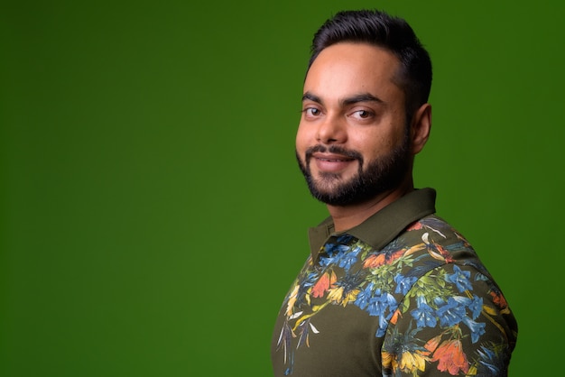 portrait of young bearded Indian man on green