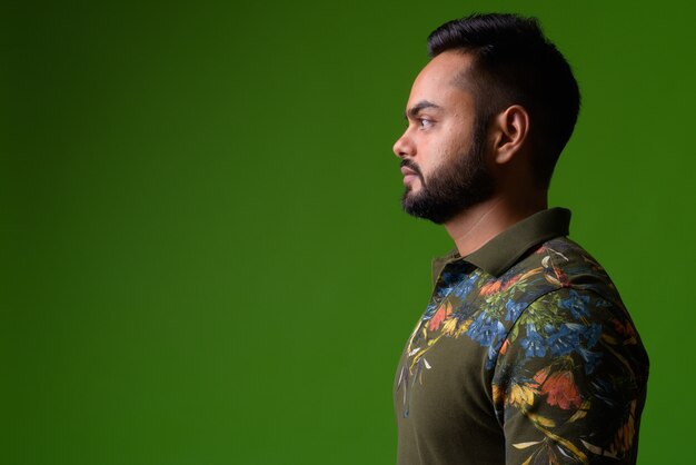 portrait of young bearded Indian man on green