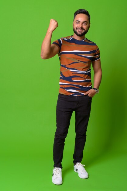 portrait of young bearded Indian man on green