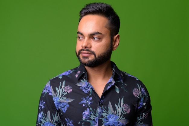 portrait of young bearded Indian man on green