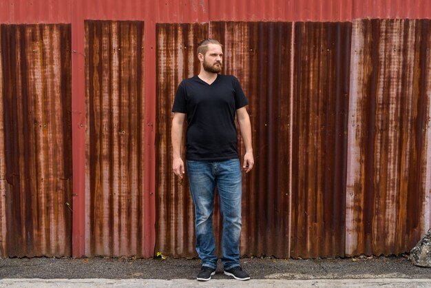 Portrait of young bearded man against old rusty sheet wall