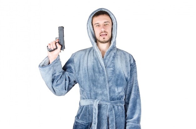 Portrait of young bearded man in blue bathrobe with black firearm