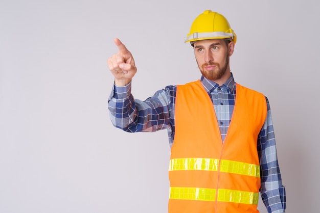 Portrait of young bearded man construction worker directing and pointing finger