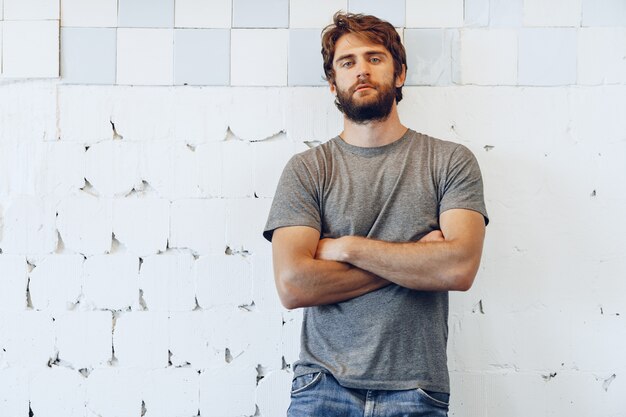 Portrait of a young bearded man standing against grunge weathered wall