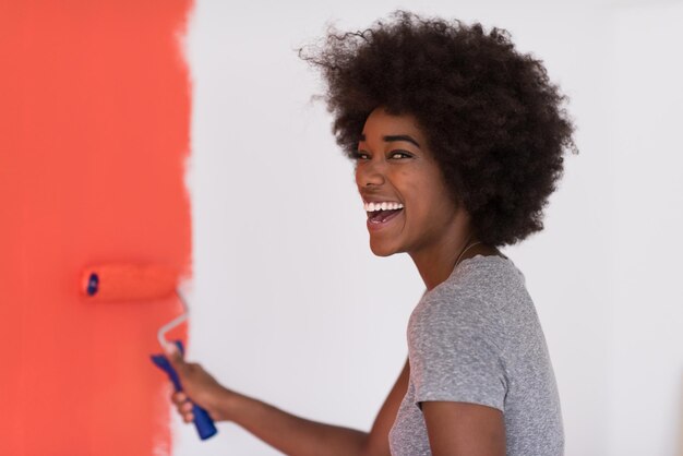 portrait of a young beautiful African American woman painting wall in her new apartment