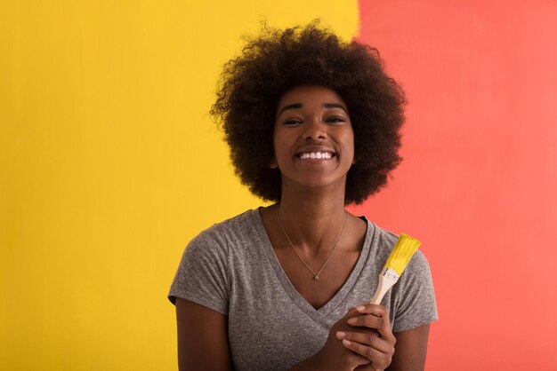 Portrait of a young beautiful african american woman painting wall in her new apartment