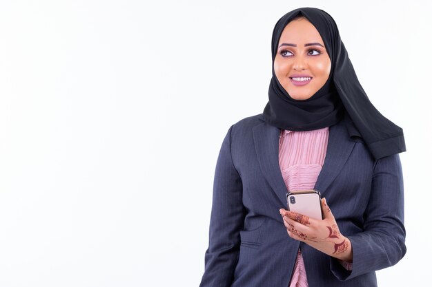 Portrait of young beautiful African Muslim businesswoman wearing hijab isolated against white wall