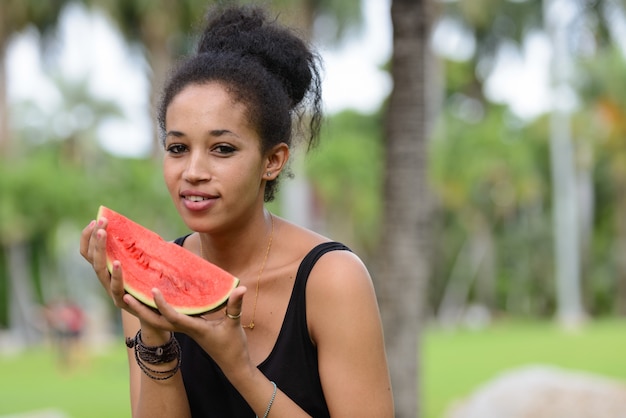 Portrait of young beautiful African woman with Afro hair relaxing at the park outdoors