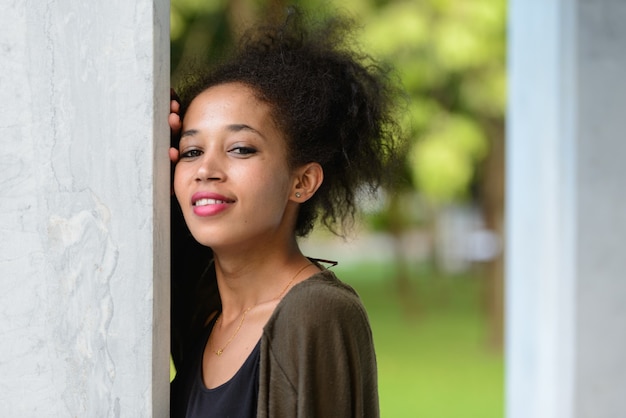 Portrait of young beautiful African woman with Afro hair relaxing at the park outdoors