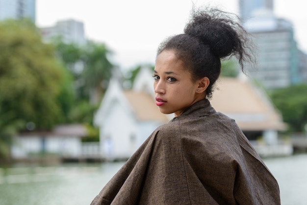 Portrait of young beautiful African woman with Afro hair relaxing at the park outdoors