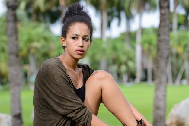 Portrait of young beautiful African woman with Afro hair relaxing at the park outdoors