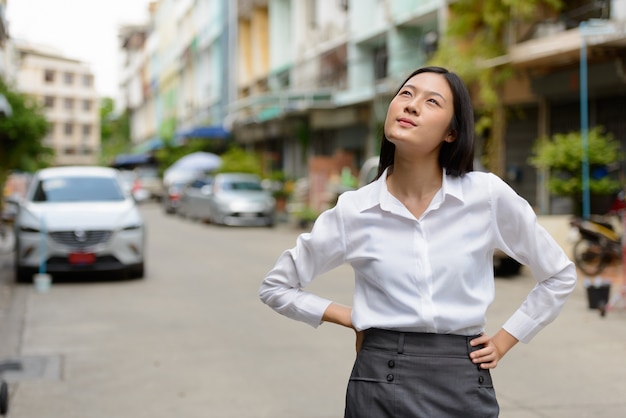 Portrait of young beautiful Asian businesswoman in the streets outdoors