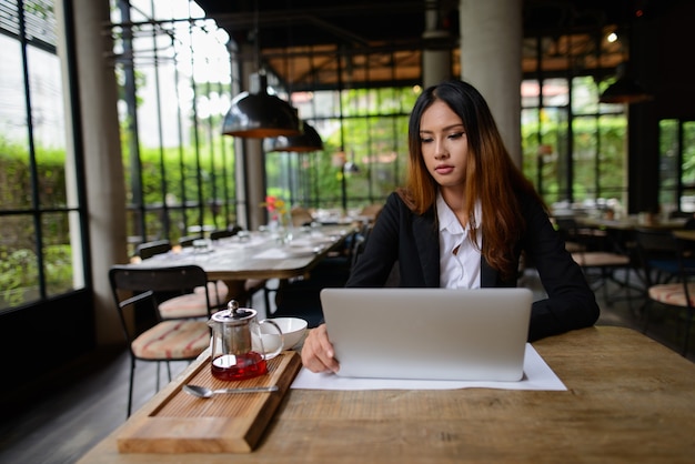 Portrait of young beautiful Asian businesswoman working at the coffee shop