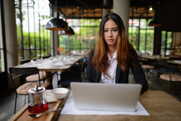 Портрет молодой красивой азиатской бизнес-леди, работающей в кафе