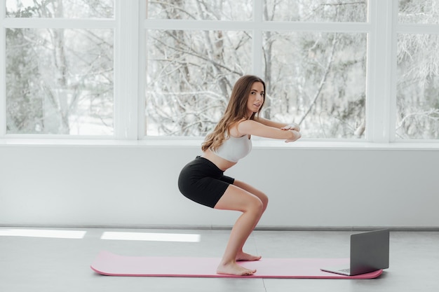 Портрет молодой красивой азиатской кореянки разогревает тренировку в позе йоги дома