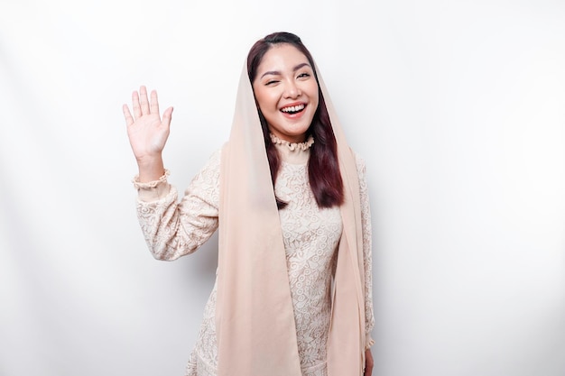 Portrait of a young beautiful Asian Muslim woman wearing a headscarf gesturing Eid Mubarak greeting