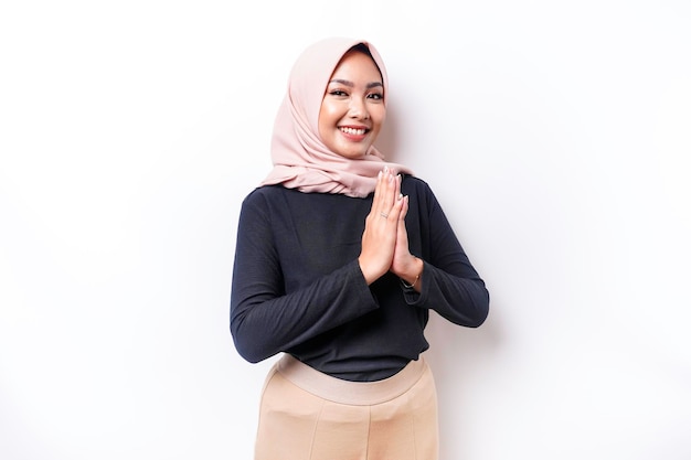 Portrait of a young beautiful Asian Muslim woman wearing a hijab gesturing Eid Mubarak greeting