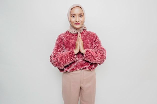 Portrait of a young beautiful Asian Muslim woman wearing a hijab gesturing Eid Mubarak greeting