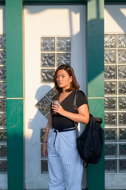Portrait of young beautiful Asian tourist woman carrying backpack at railway station