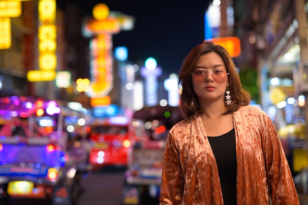 Portrait of young beautiful asian tourist woman exploring chinatown in bangkok