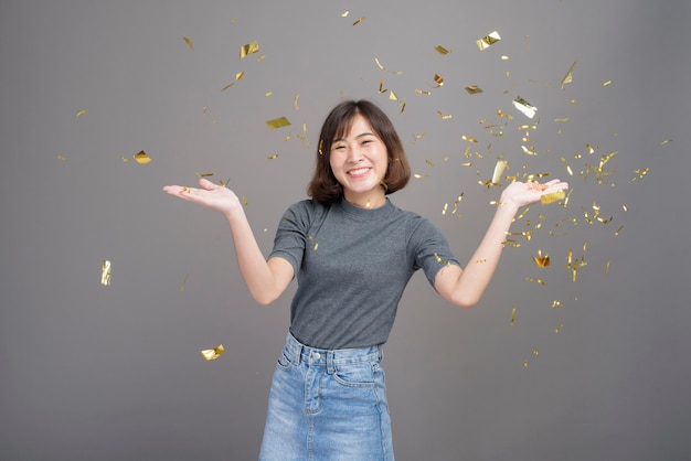 A portrait of young beautiful asian woman celebrating and playing paper shoot isolated gray background studio, Christmas and New Year Concept.