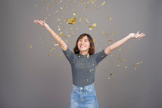 A portrait of young beautiful asian woman celebrating and playing paper shoot