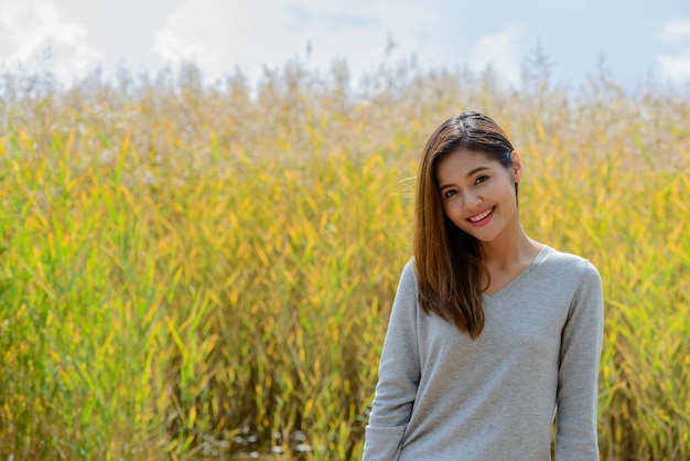 Portrait of young beautiful Asian woman relaxing in the fields of tall grass in nature