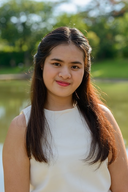 Foto ritratto di giovane bella donna asiatica che si distende al parco all'aperto