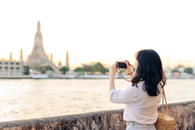 태국 방콕의 왓 아룬(Wat Arun) 일몰 뷰 포인트에서 여행하는 동안 웃고 있는 젊은 아름다운 아시아 여성의 초상화