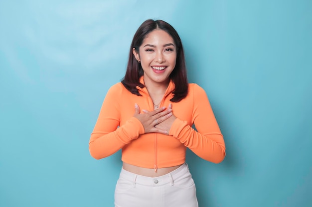 Portrait of Young beautiful Asian woman standing and smiling at the camera isolated on blue background