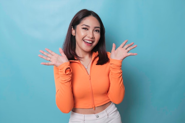 Portrait of Young beautiful Asian woman standing and smiling at the camera isolated on blue background