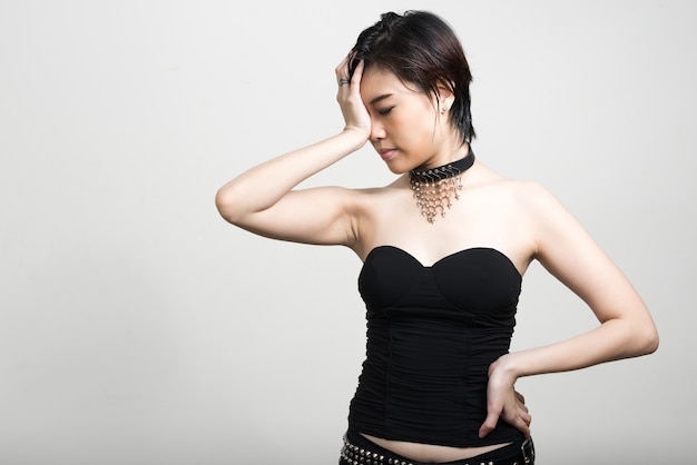 Portrait of young beautiful Asian woman with short hair against white wall