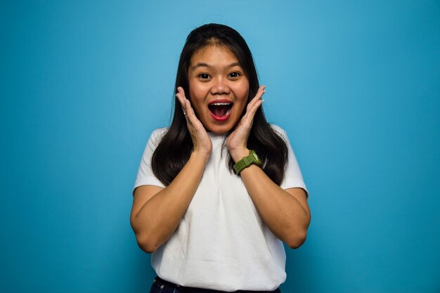 Portrait of Young beautiful asian women using white Tshirt isolated on blue wow gesture