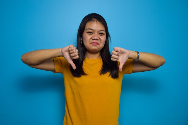 Portrait of Young beautiful asian women with blue isolated background thumbs down gesture