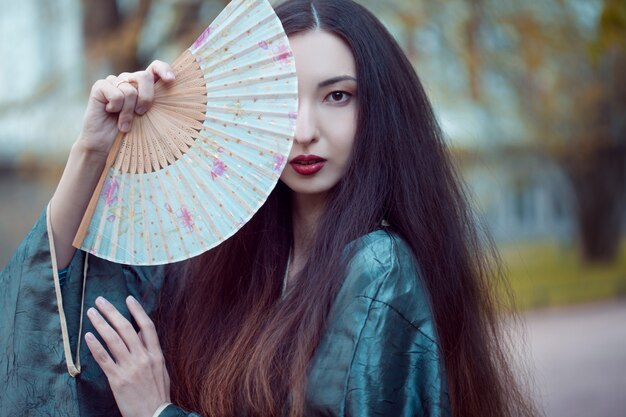 Portrait of young beautiful Asians in grey kimono and with a fan