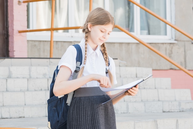 Portrait of a young, beautiful, attractive and intelligent schoolgirl in wearing spectacles in a white shirt giving a presentation in a lecture outdoor. she is smiling as she is presenting