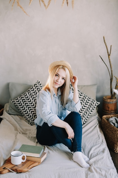 portrait of a young beautiful blonde girl in bed in the morning at home in scandinavian interior good morning lifestyle