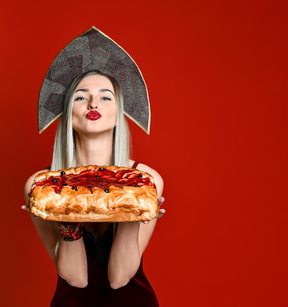 Portrait of a young beautiful blonde in headscarf holding a delicious homemade cherry pie