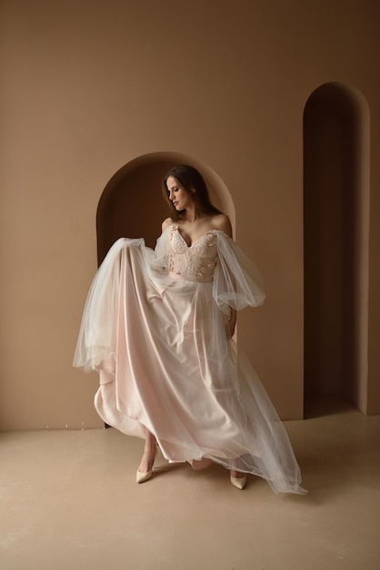 Portrait of a young beautiful bride in full growth Girl posing in a room near the window