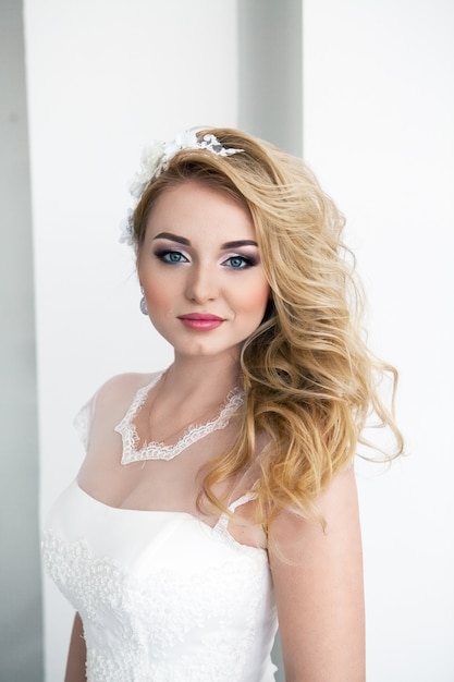 Portrait of young beautiful bride over white wall