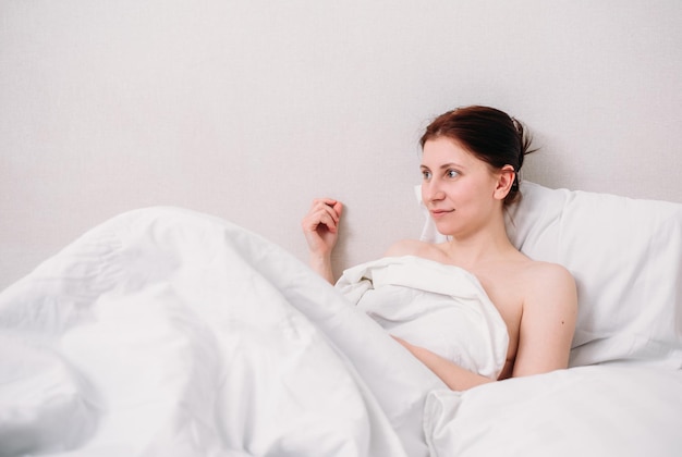 Portrait of a young beautiful brunette lying in bed wearing underwear