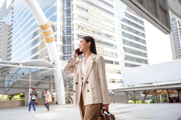 Portrait of young beautiful businesswoman using smartphone in modern city