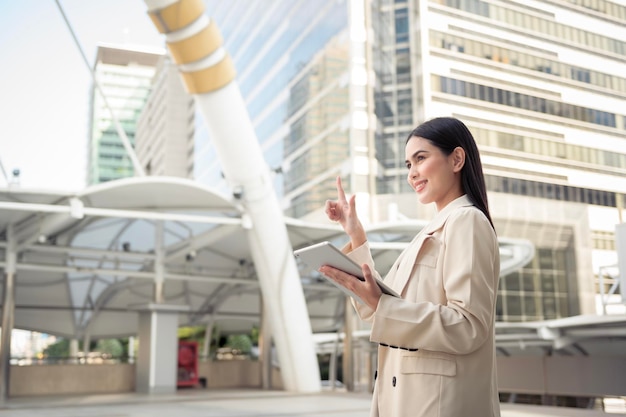 Portrait of young beautiful businesswoman using tablet in modern city