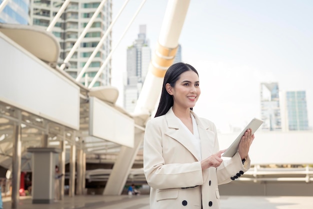 Portrait of young beautiful businesswoman using tablet in modern city